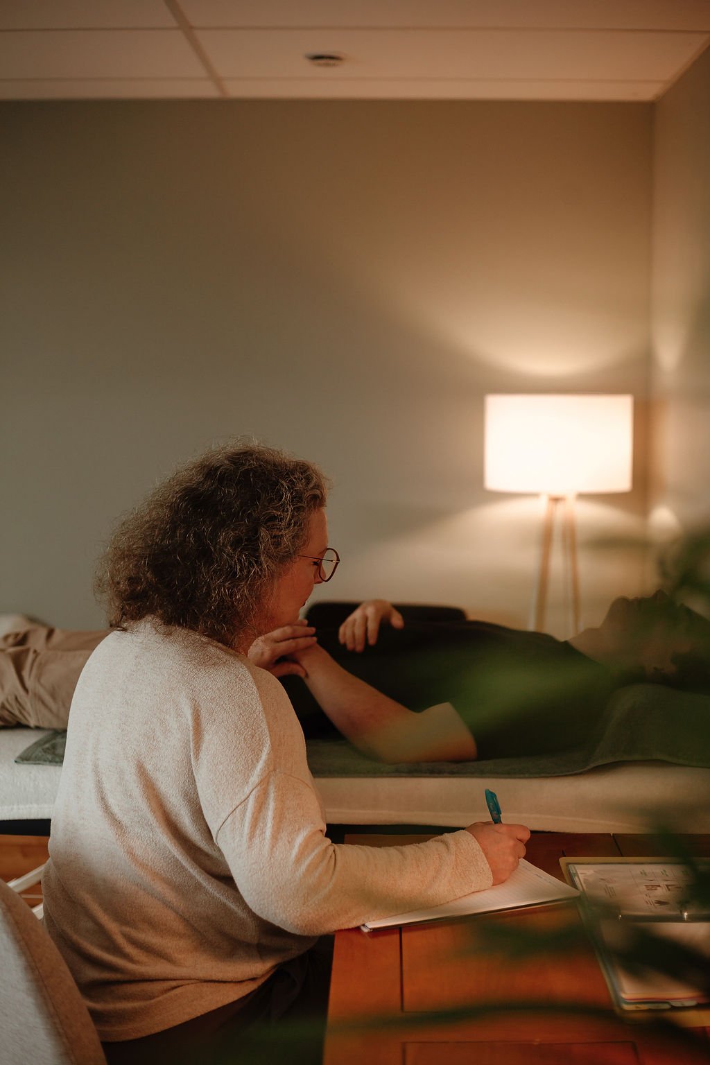 Test musculaire sur une personne habillée, allongée sur une table de massage, et prise de notes de Stéphanie Soreau-Dinis