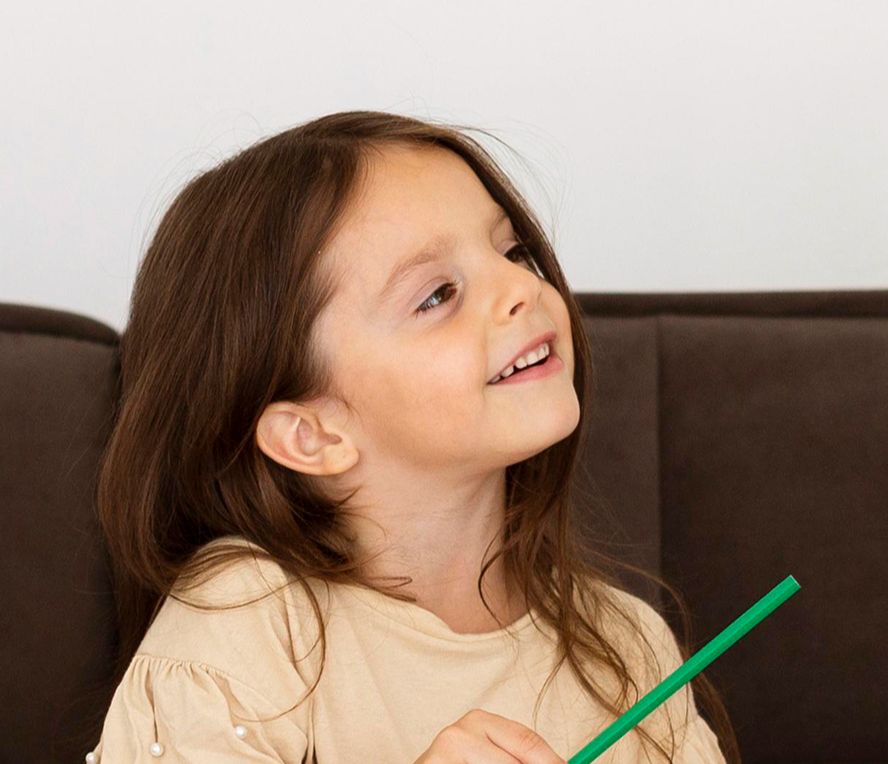 Une enfant assise sur un canapé qui écoute son histoire grâce à la méthode Raconte-moi mon histoire